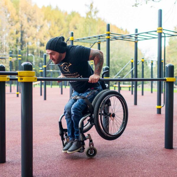 Sportler mit Handicap macht Barrenstütze an der Parallelbarren mit unterschiedlicher Breite