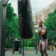 Mann beim Boxtraining mit einem Kenguru Pro Boxsack in einem modernen Outdoor-Fitnesspark.