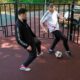 Zwei junge Männer spielen Panna Fußball auf einem Outdoor-Kleinspielfeld mit rotem Bodenbelag