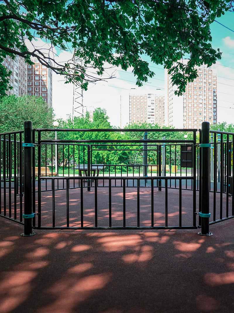Panna-Fußballplatz im Park mit robustem Metallgitter und schattigen Bäumen im Hintergrund