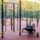 Rollstuhlfahrer führt Liegestütze an einer niedrigen Stange einer Calisthenics Anlage aus