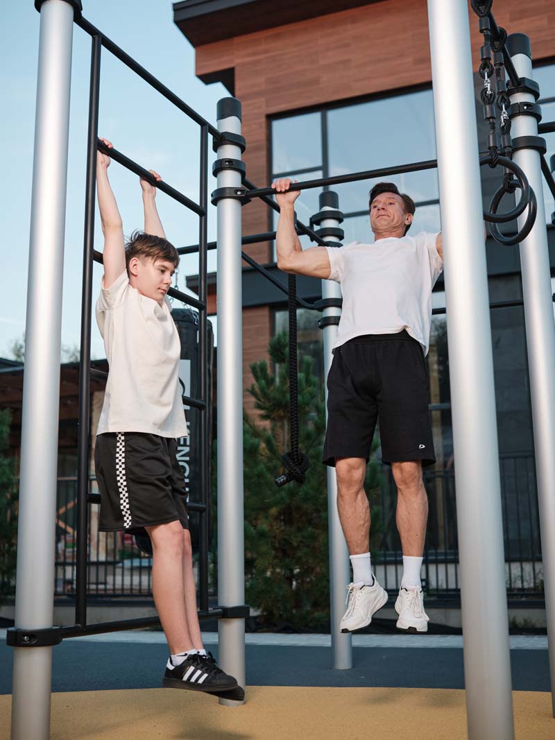 Kind und Erwachsener trainieren gemeinsam an einer Calisthenics Anlage von Kenguru Pro im Freien