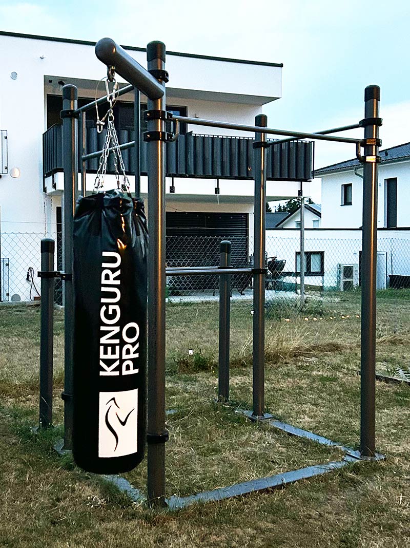 Mobile Calisthenics-Station mit Boxsack von Kenguru Pro: Robuste Outdoor-Trainingsanlage für funktionelles Kraft- und Ausdauertraining. Die kompakte Konstruktion mit Klimmzugstangen und einem hochwertigen Boxsack eignet sich perfekt für den Garten oder öffentliche Sportflächen. Ideal für vielseitige Workouts im Freie