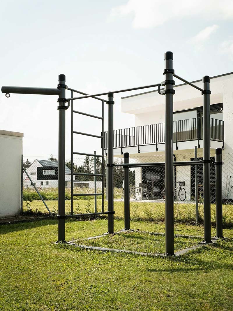 Mobile Calisthenics-Station von Kenguru Pro: Vielseitige Outdoor-Trainingsanlage für funktionelles Kraft- und Ausdauertraining im eigenen Garten oder auf öffentlichen Flächen. Die robuste Stahlkonstruktion mit Klimmzugstangen, Sprossenwand und Erweiterungsmöglichkeiten bietet optimale Bedingungen für ein effektives Workout im Freien.