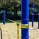 Zwei blaue Slackline Pfosten von Kenguru Pro spannen ein gelbes Trainingsband zum Balancieren im öffentlichen Park