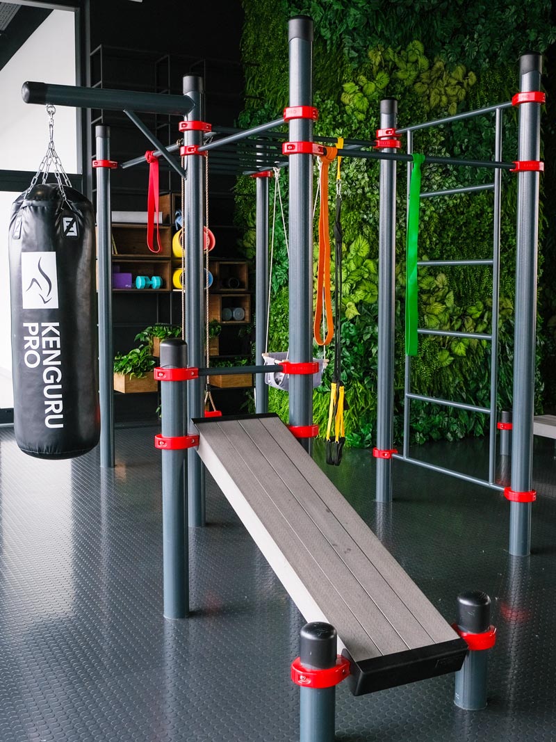 Indoor Calisthenics Anlage von Kenguru Pro mit Schrägbank, Boxsack und Zubehör im modernen Trainingsraum