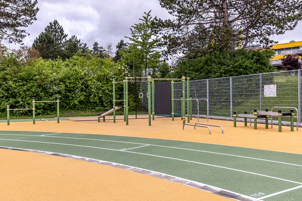 Calisthenics Park am Berufsschulzentrum Ravensburg – ausgestattet mit vielfältigen Trainingsgeräten wie Klimmzugstangen, Turnringen, Schrägbank, Sprossenwand, Hürden und Dip-Barren. Die Anlage steht auf einem gelenkschonenden Gummiboden direkt an einer Laufbahn und ist ideal für funktionelles Outdoor-Training im schulischen und öffentlichen Bereich. Umgeben von viel Grün bietet der Park optimale Bedingungen für Kraft- und Koordinationstraining im Freien.