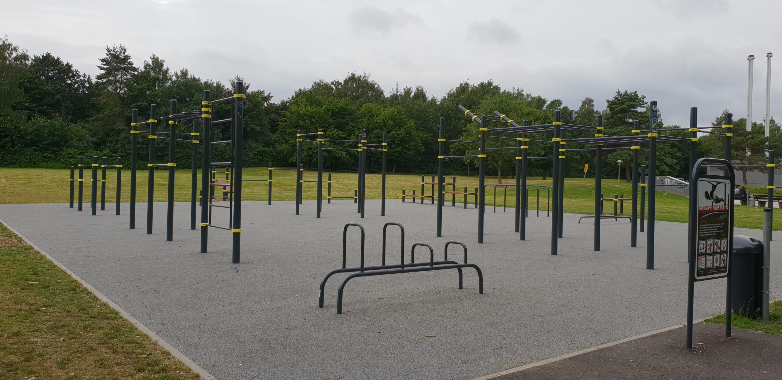 Großer Calisthenics Park Detmold mit Klimmzugstangen, Dip-Barren und Monkey Bars auf Outdoor-Fitnessanlage im Grünen.