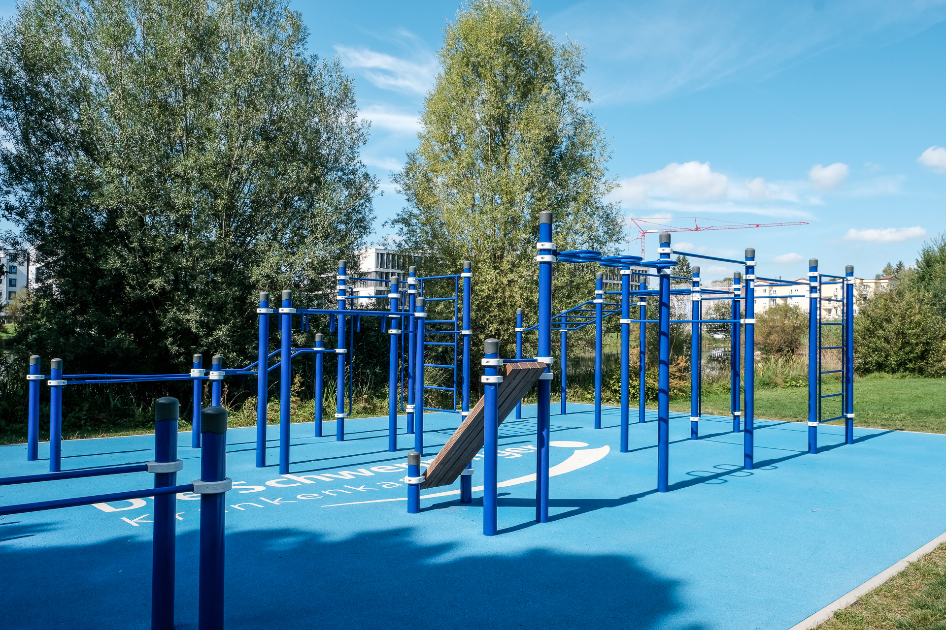 Calisthenics Park Villingen-Schwenningen mit blauen Klimmzugstangen, Monkey Bars und Trainingsstationen auf moderner Outdoor-Fitnessanlage im Park.