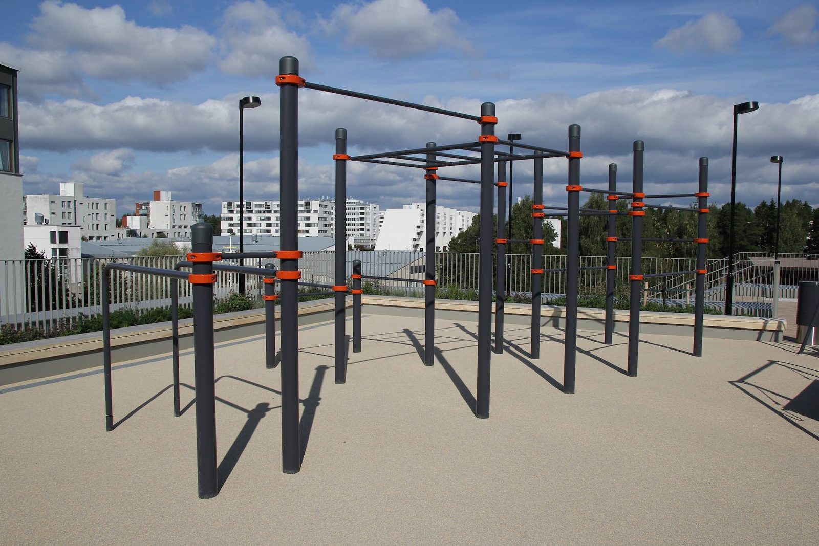 Calisthenics Anlage von KENGURU PRO auf einer erhöhten Fläche mitten in der Stadt mit Reckstangen in mehreren Höhen, Parallelbarren und Hangelleiter