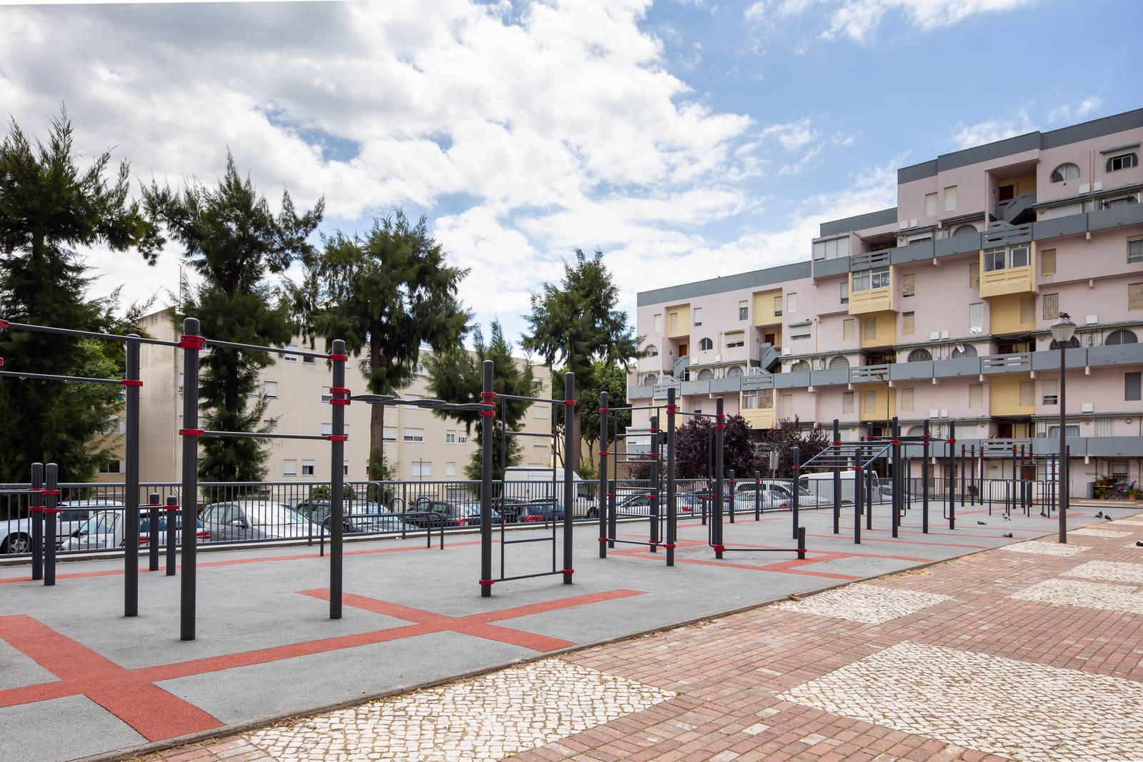 Calisthenics Anlage von KENGURU PRO zwischen Wohnhäusern im Quartier Marvila in Lissabon mit Reckstangen in mehreren Höhen auf gepflastertem Platz