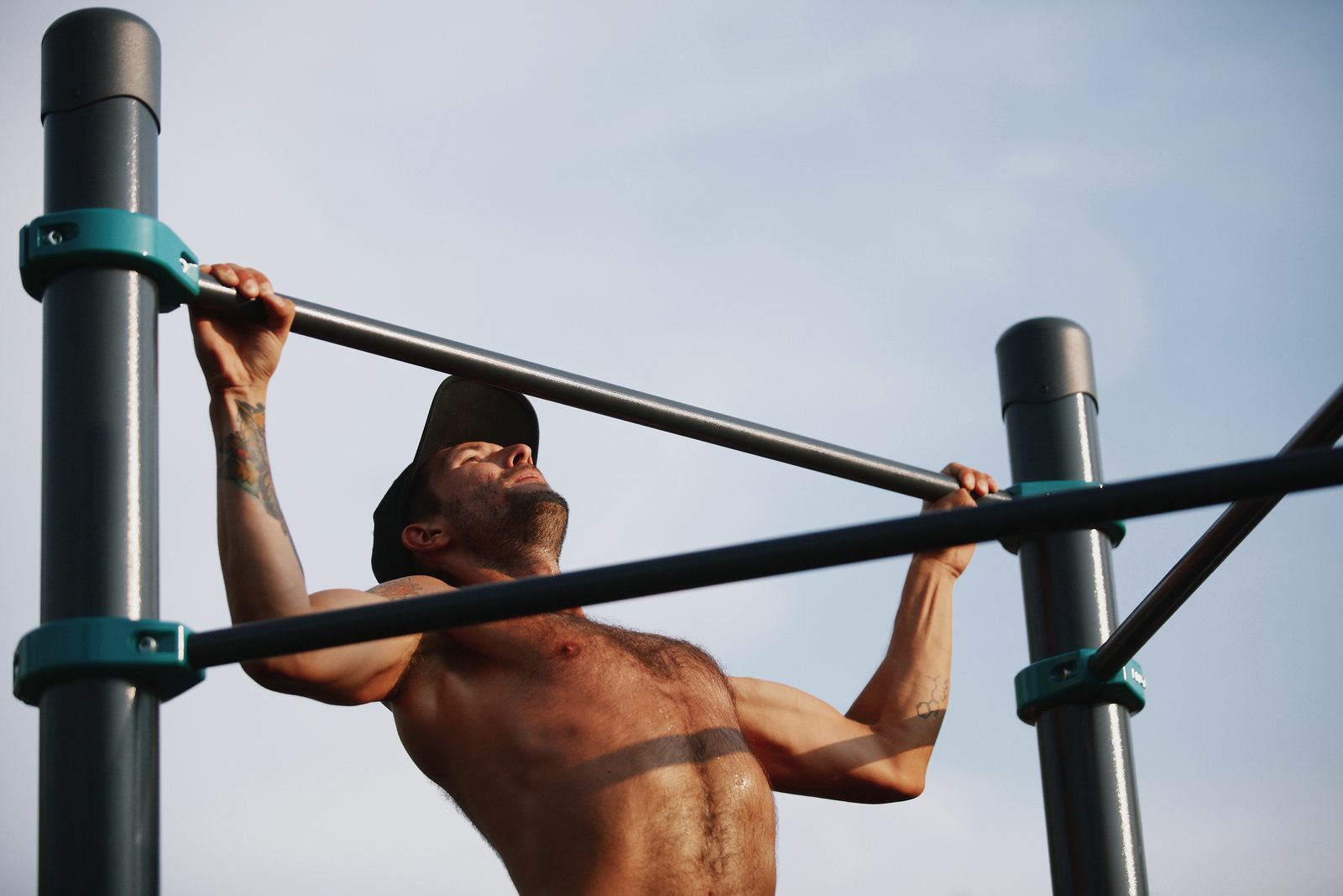 Sportler beim Klimmzug an der Reckstange einer Calisthenics Anlage von KENGURU PRO, Nahaufnahme mit Klemmringen