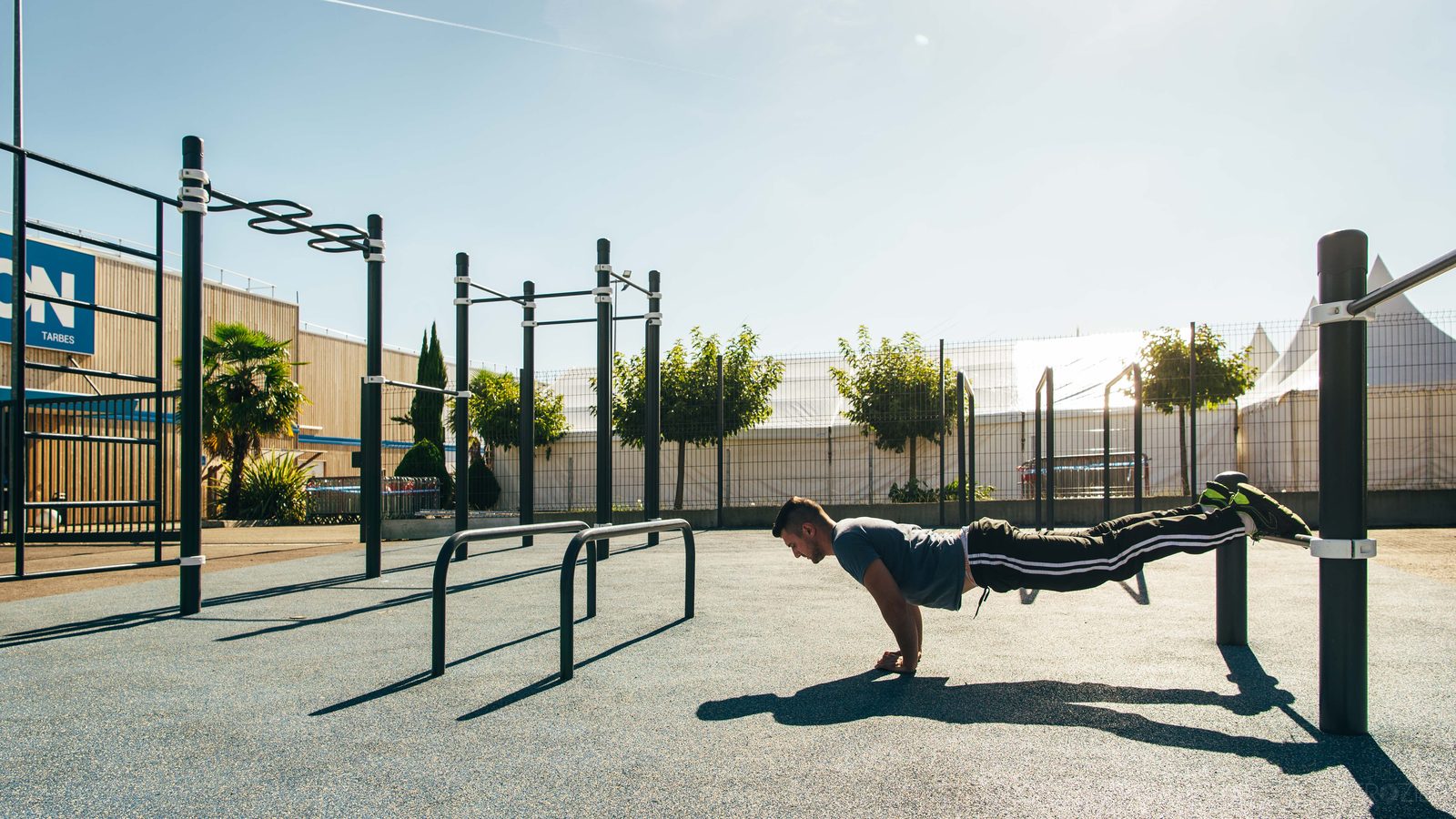 Sportler macht Liegestütze mit den Füßen auf einem niedrigen Holm an einer Calisthenics Anlage von KENGURU PRO