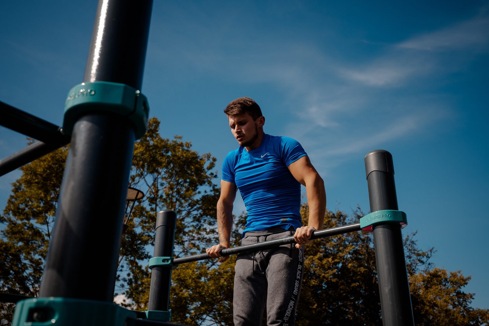 Sportler im Stütz auf der Reckstange, Endposition des Muscle-ups, an einer Calisthenics Anlage von KENGURU PRO