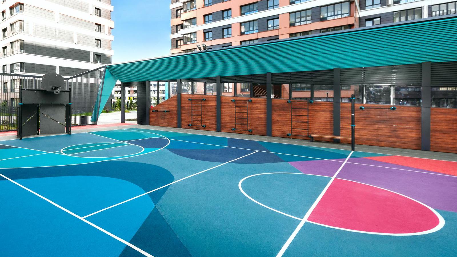 Jugendplatz im Wohnquartier: buntes Multisportfeld mit Basketballkorb, daneben überdachte Wand mit Calisthenics Geräten von KENGURU PRO