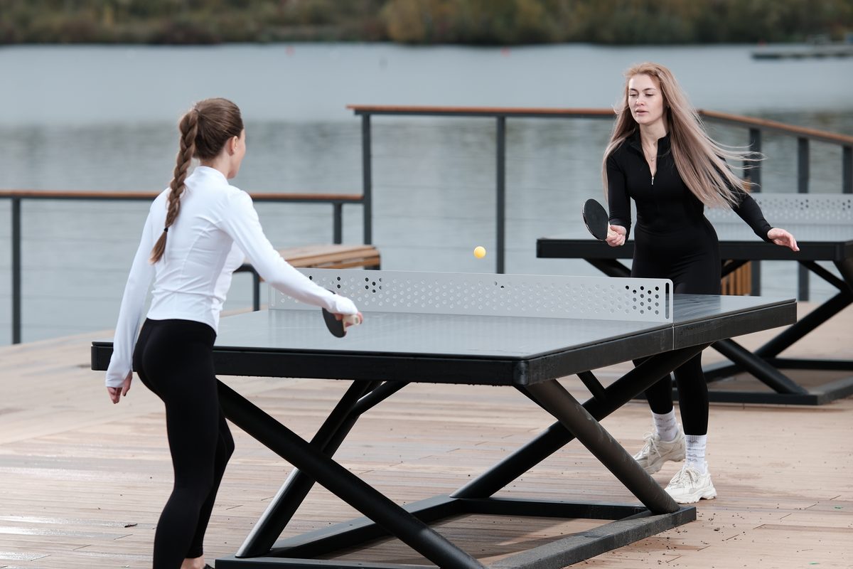 Ballwechsel an einer Tischtennisplatte Outdoor von KENGURU PRO mit perforiertem Metallnetz und gekreuztem Metallgestell